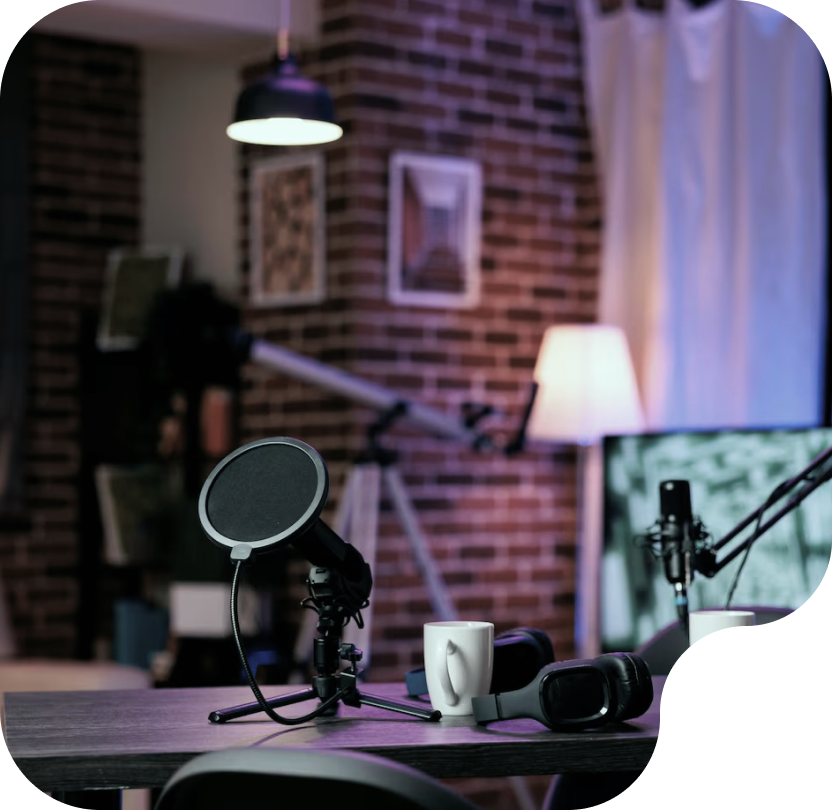 Podcast recording setup featuring a microphone, pop filter, headphones, and a coffee mug in a cozy studio environment with brick walls and soft lighting.