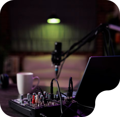 Podcasting studio setup featuring a microphone, audio mixer, laptop, and coffee cup, highlighting a professional recording environment for creators at PodcastCrew in Robbinsdale, MN.