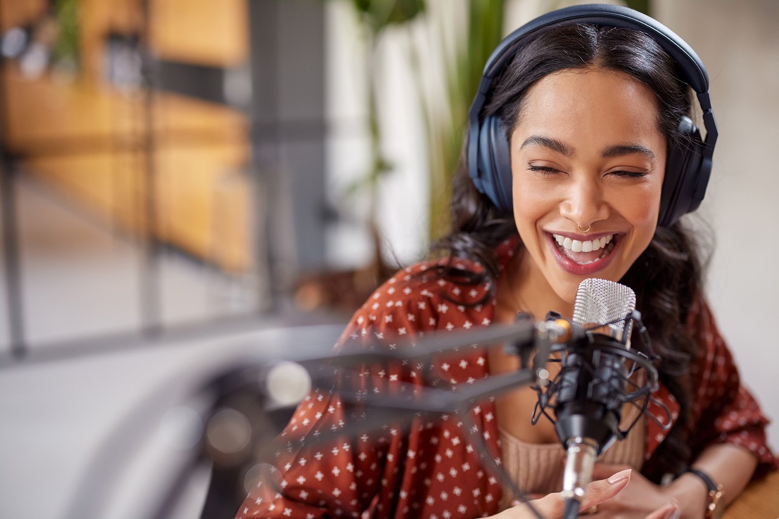 Joyful young woman recording live podcast