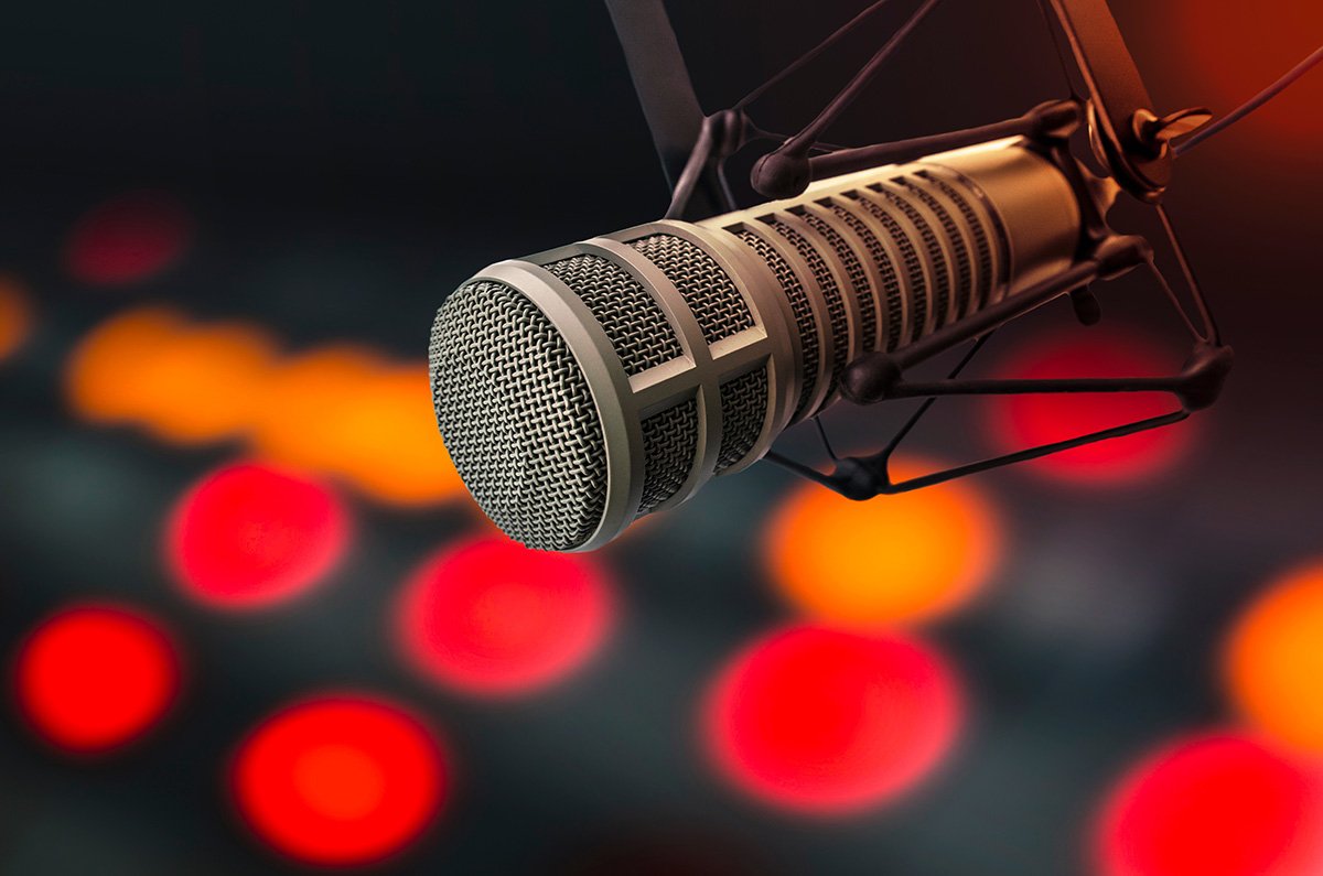 Microphone in focus with blurred colorful background, representing essential podcasting equipment for high-quality audio.