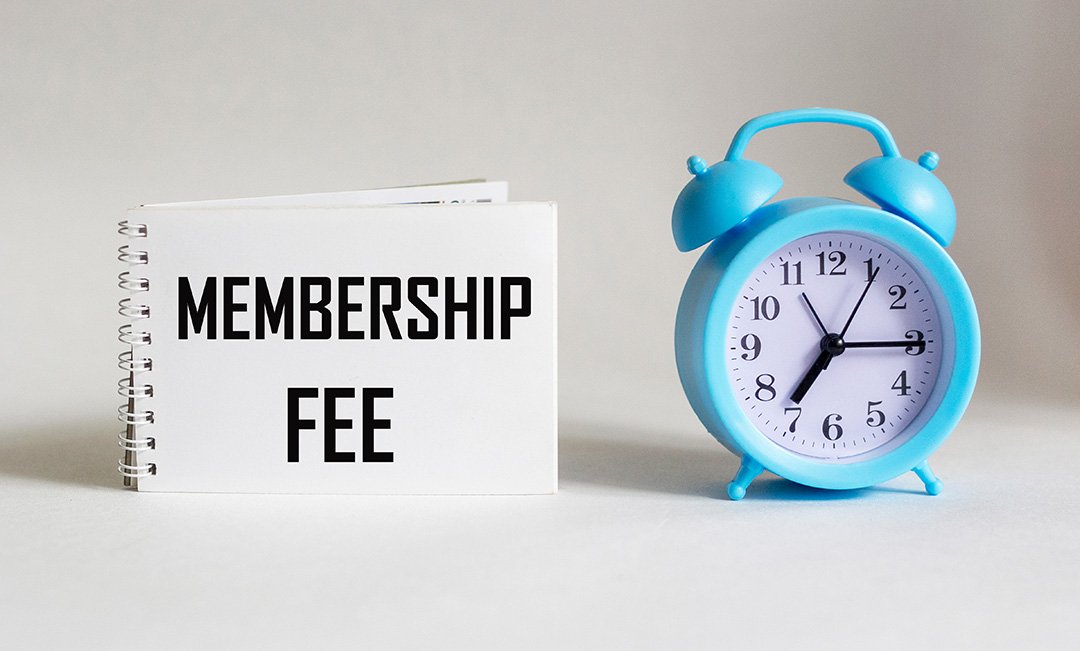 Membership fee sign next to a blue alarm clock, representing pricing considerations for podcast studio membership plans.