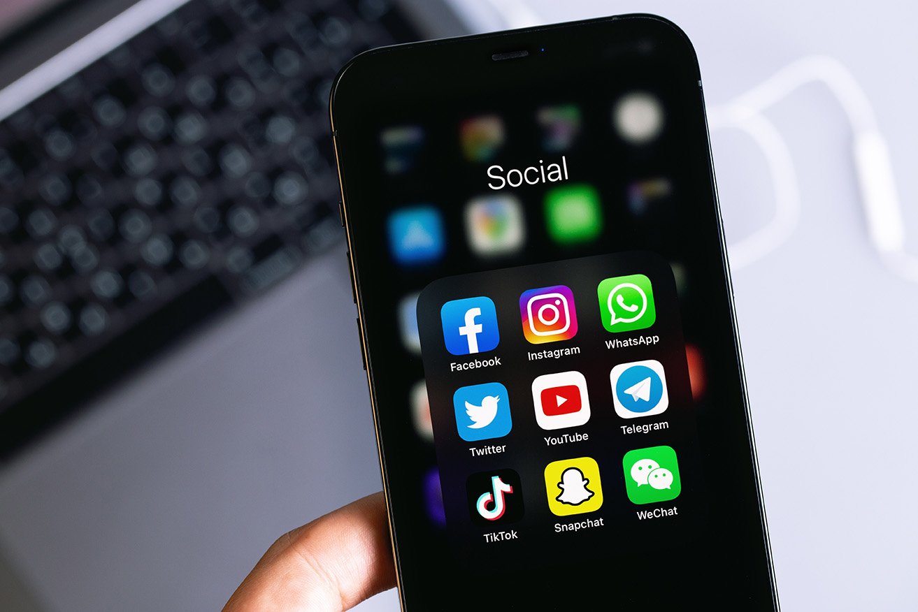 Smartphone displaying social media app icons including Facebook, Instagram, Twitter, and TikTok, emphasizing social media engagement for podcast promotion.