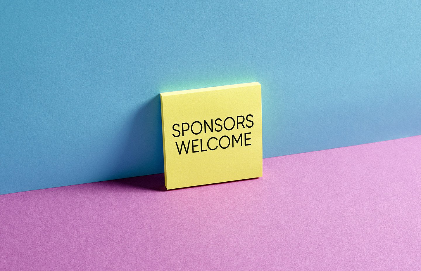 Yellow sticky note with "SPONSORS WELCOME" text on a colorful background, symbolizing podcast monetization strategies through sponsorships and advertising.