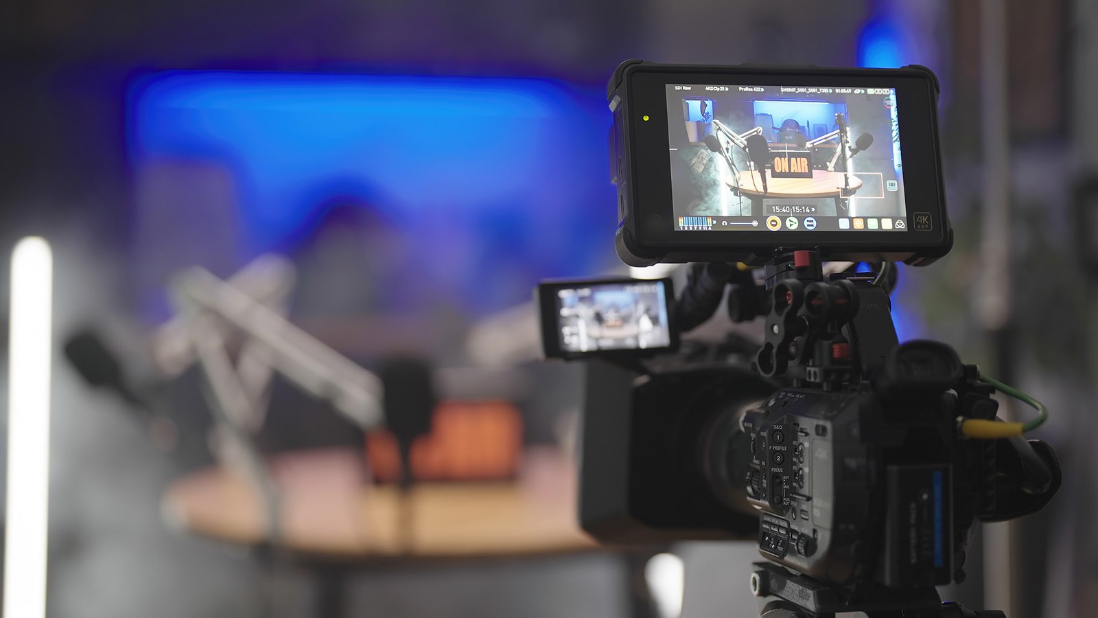 Video camera setup in professional podcast studio, featuring on-air sign, microphones, and dynamic lighting for video podcasts.